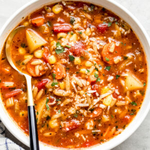 white bowl with vegetable soup and a side of a spoon.