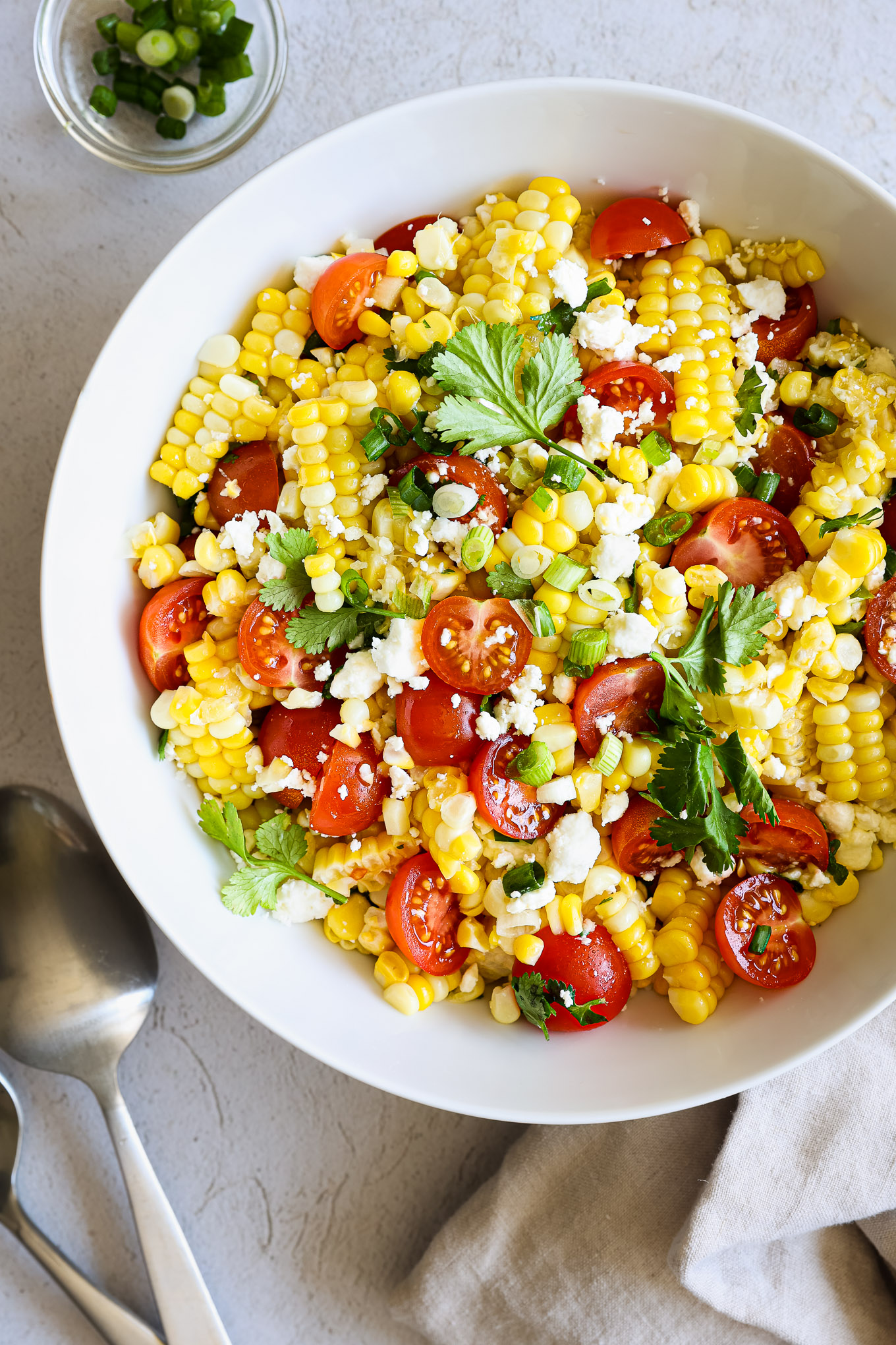 corn salad with tomatoes, feta, and cilantro in a white bowl.
