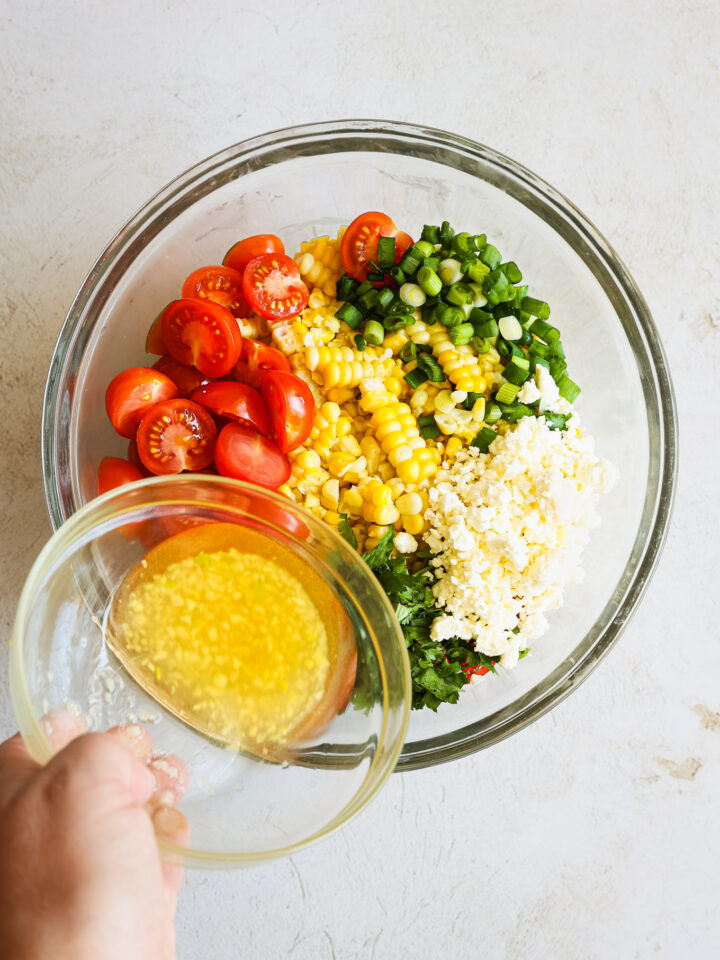 dressing with corn salad in a glass bowl.