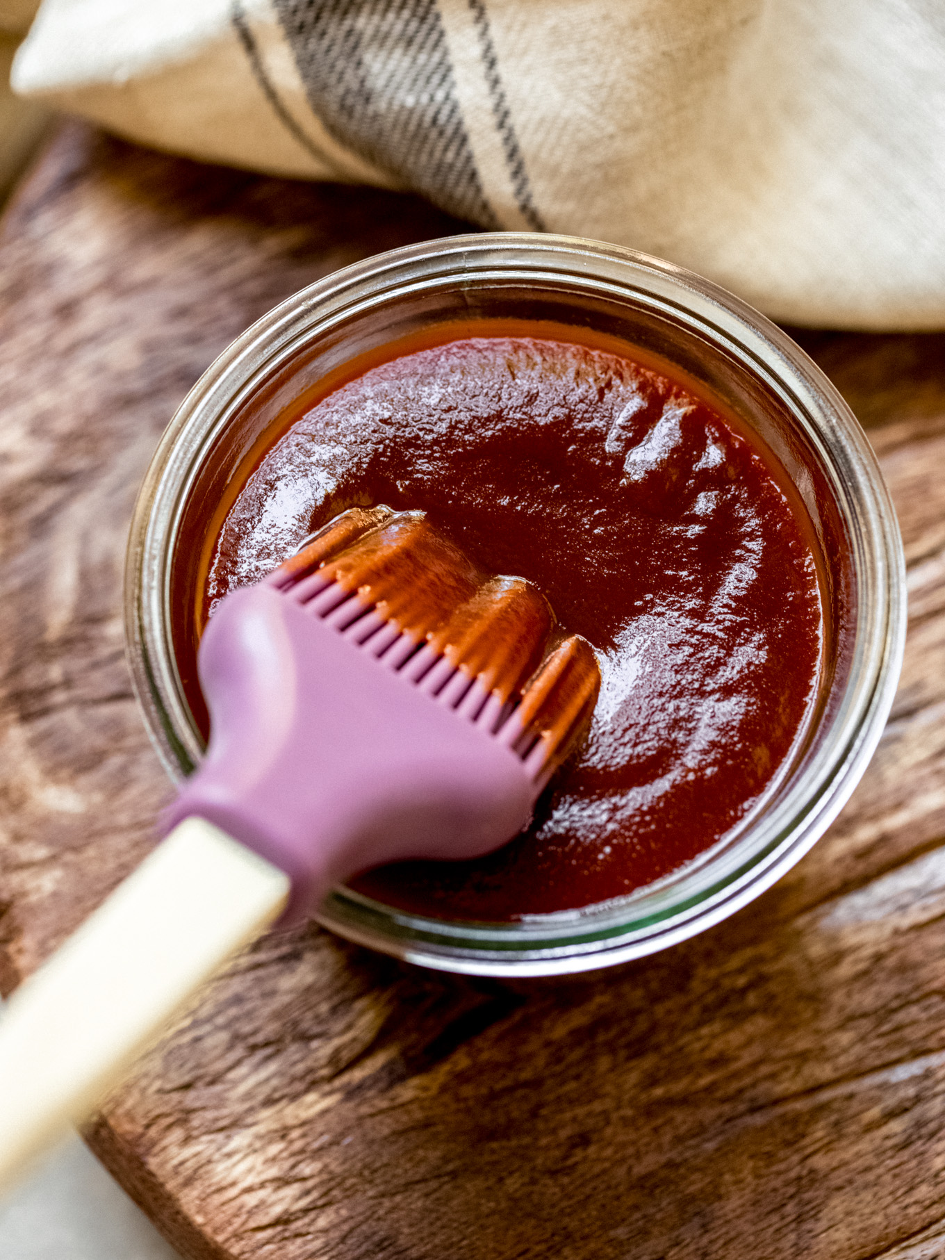 bbq sauce in a glass jar with a silicone brush dipped.