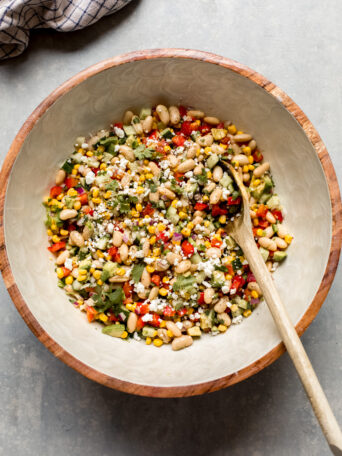 white bean salad in a bowl with a wooden spoon.