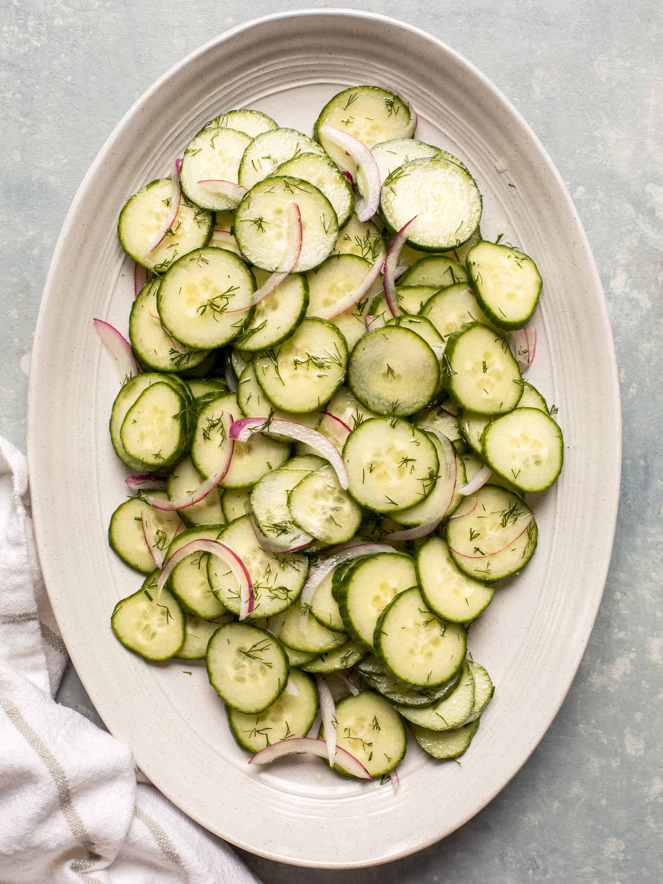 cucumber onion salad on an oval platter.