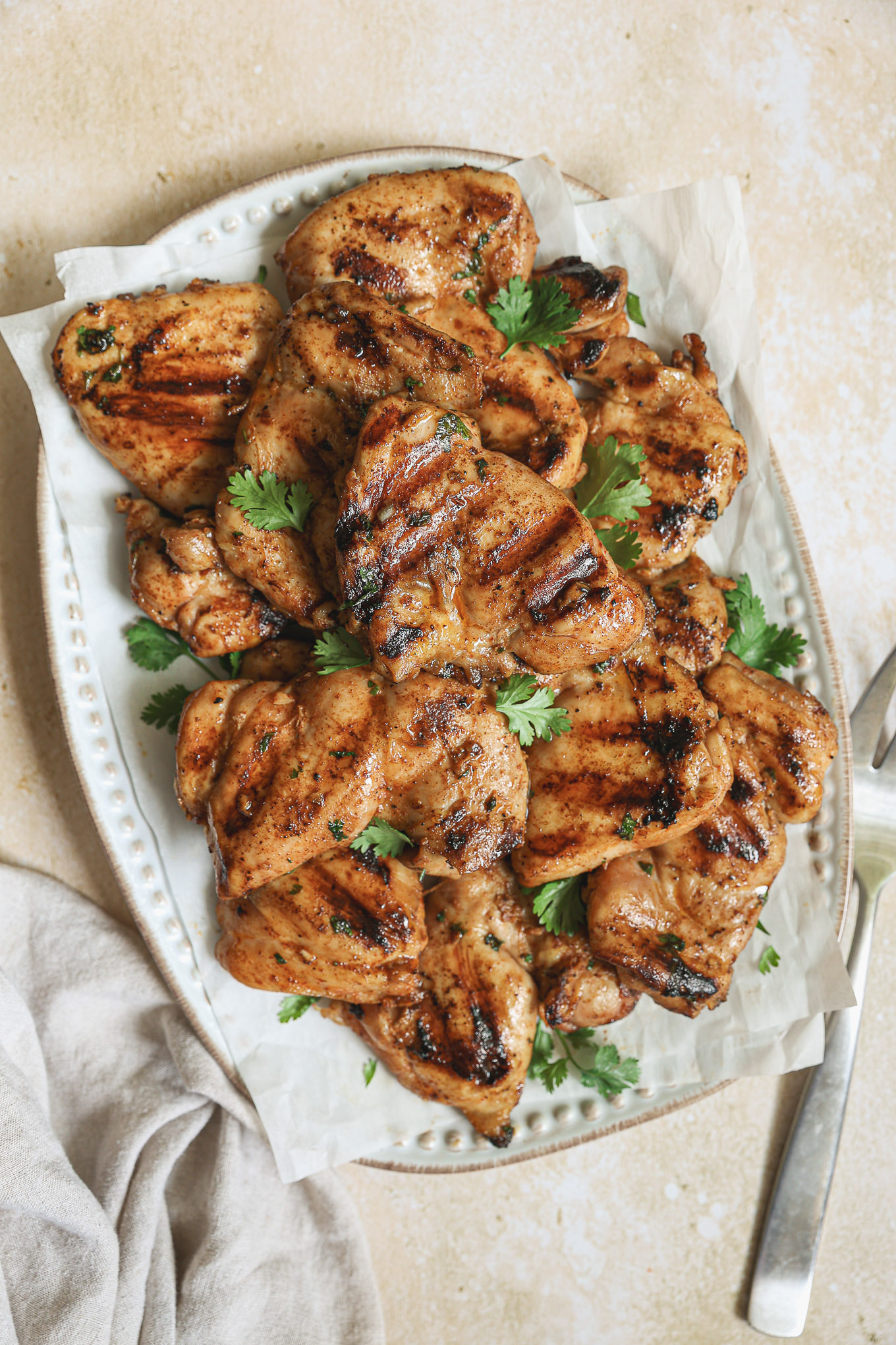 grilled chicken thighs on a platter garnished with cilantro.