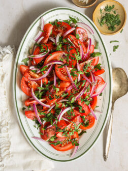 tomato and onion salad on white oval platter.