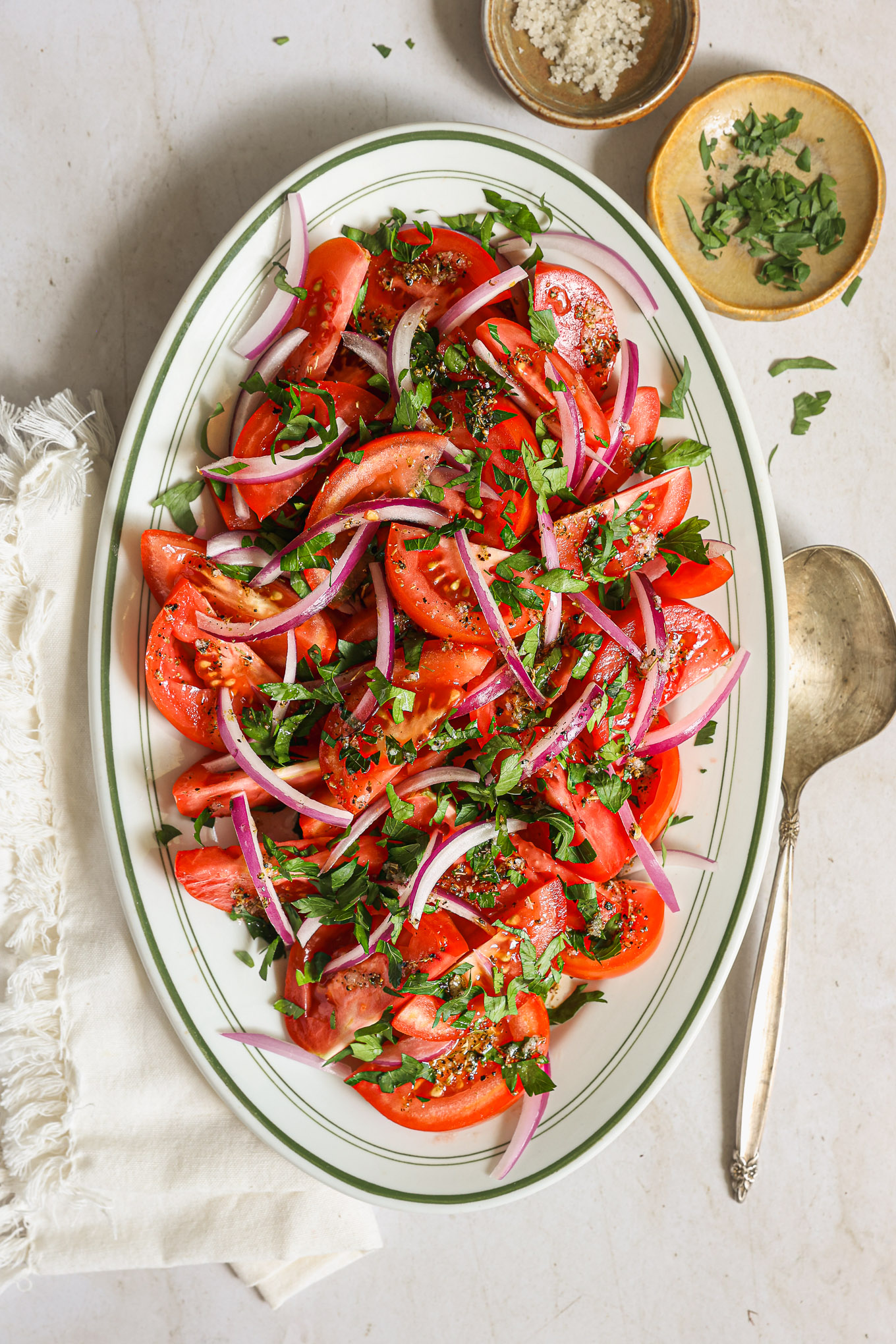 tomato and onion salad on white oval platter.