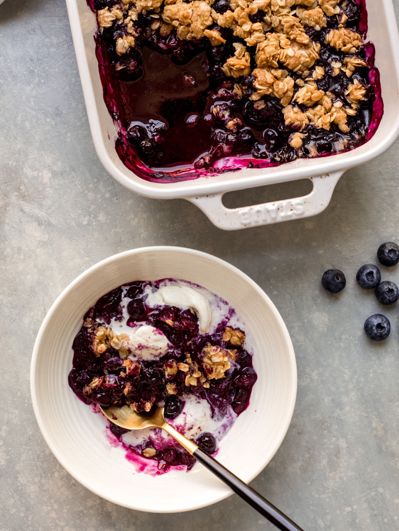 blueberry crisp recipe in a bowl topped with ice cream.