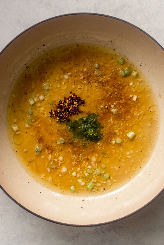 chili flakes and lime zest with butter inside pan.