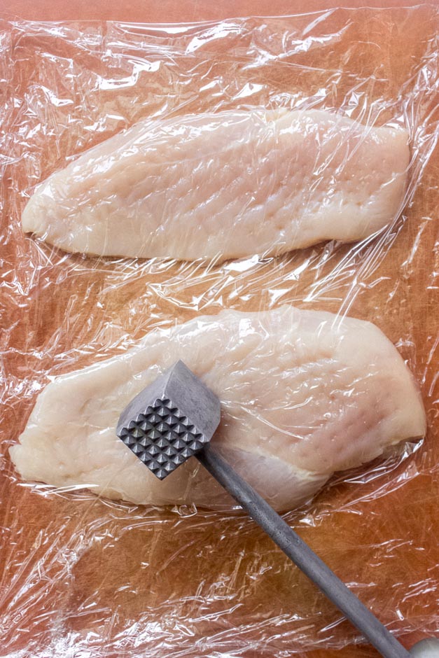 chicken breast between plastic wrap.