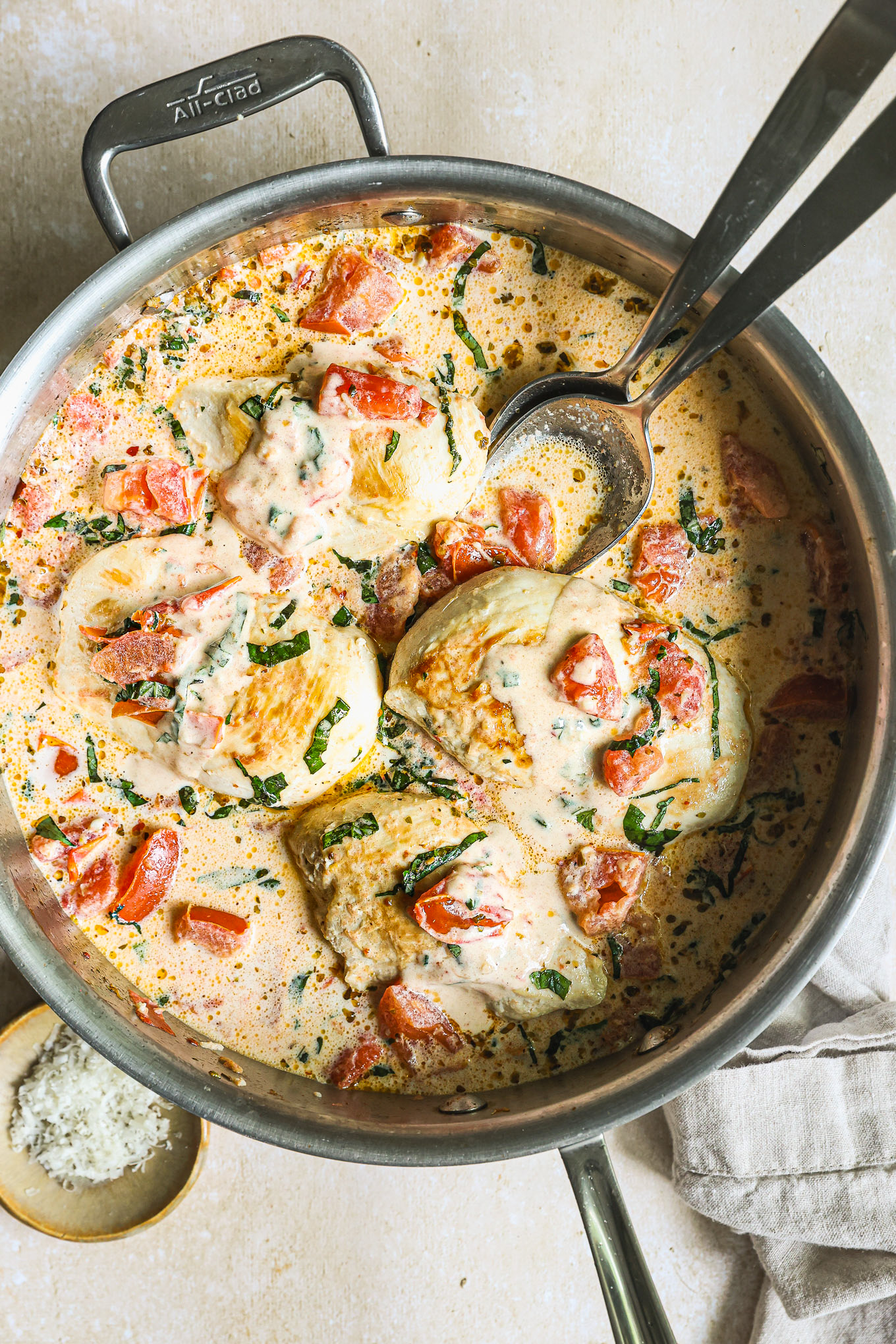 chicken breast topped with tomato cream sauce in a saute pan. 