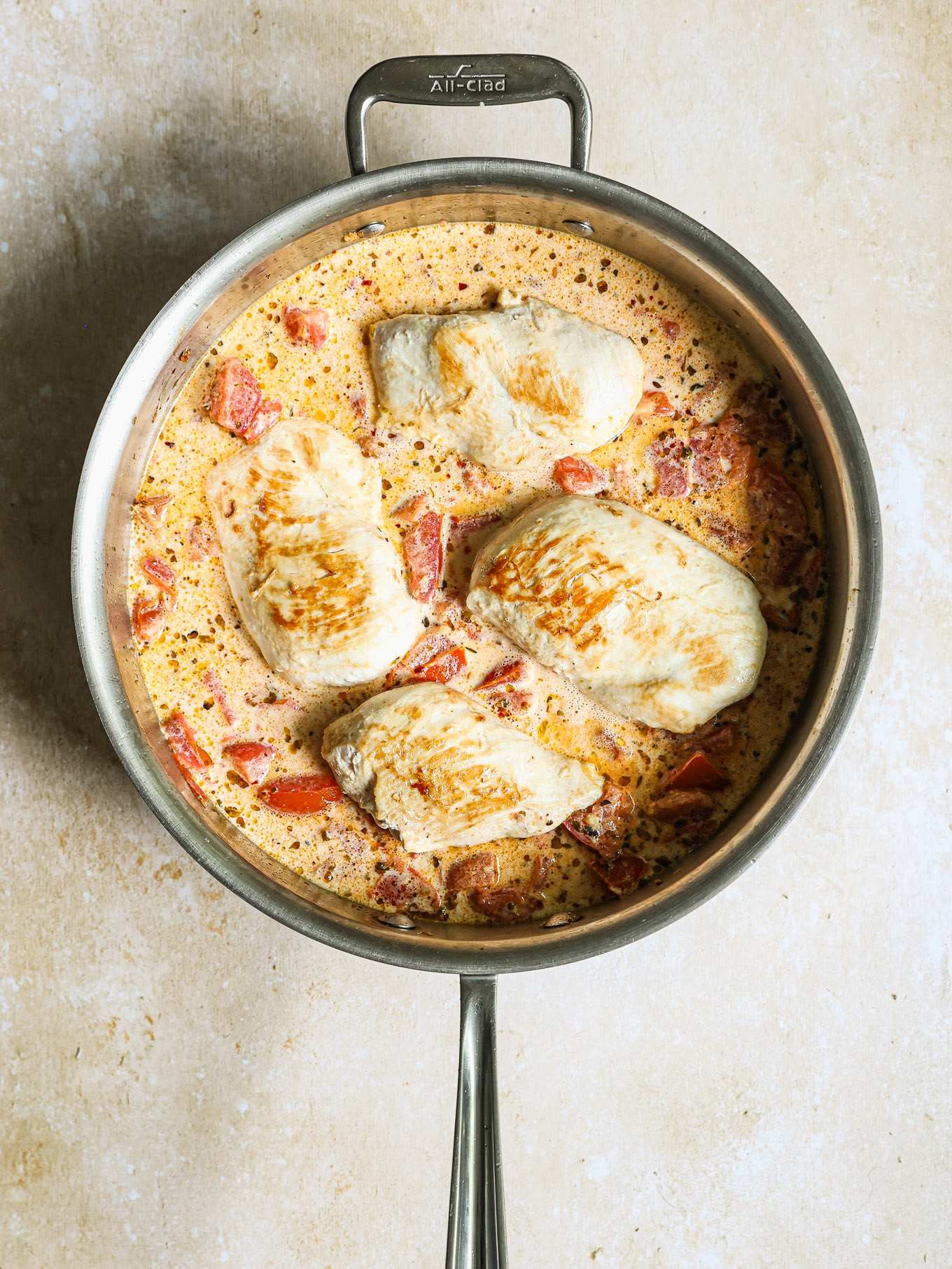 chicken breast with cream sauce in a pan.