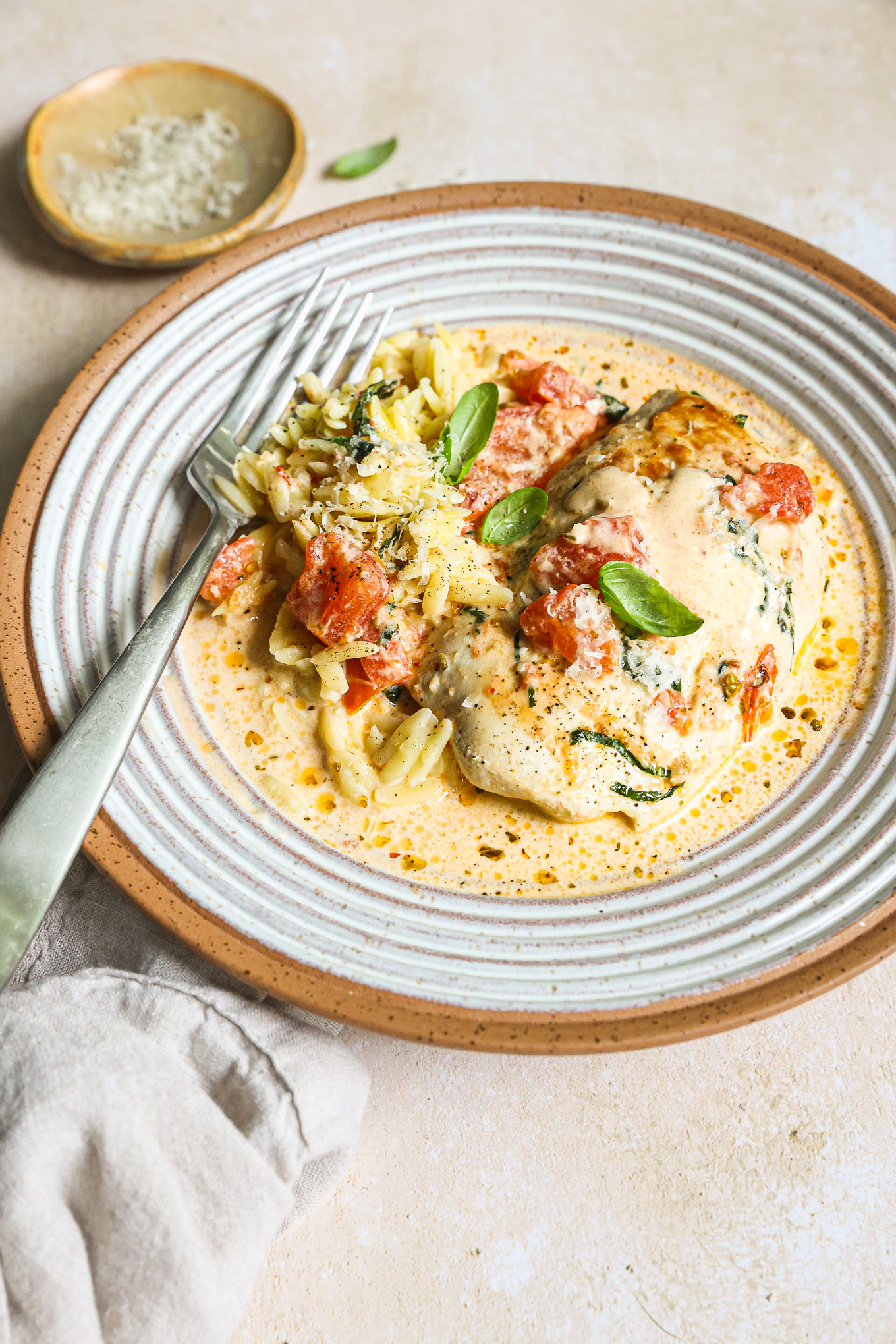 chicken breast in tomato cream sauce over orzo in a bowl.