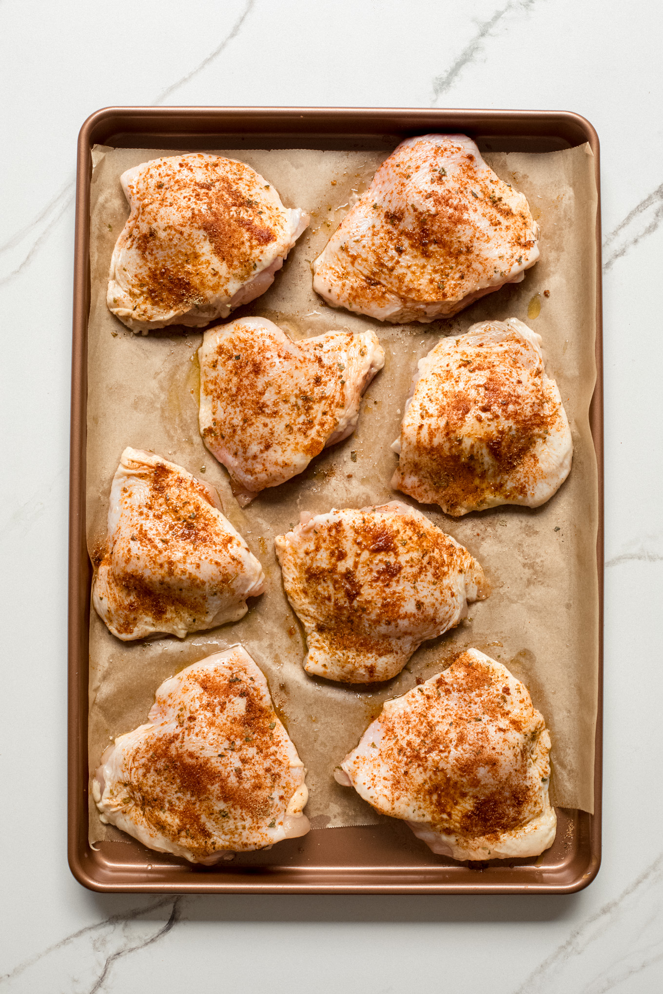 raw chicken thighs skin side up on a baking sheet.