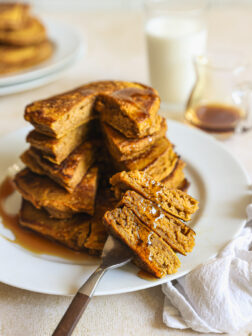 stacked and cut pumpkin spice pancakes on a plate.