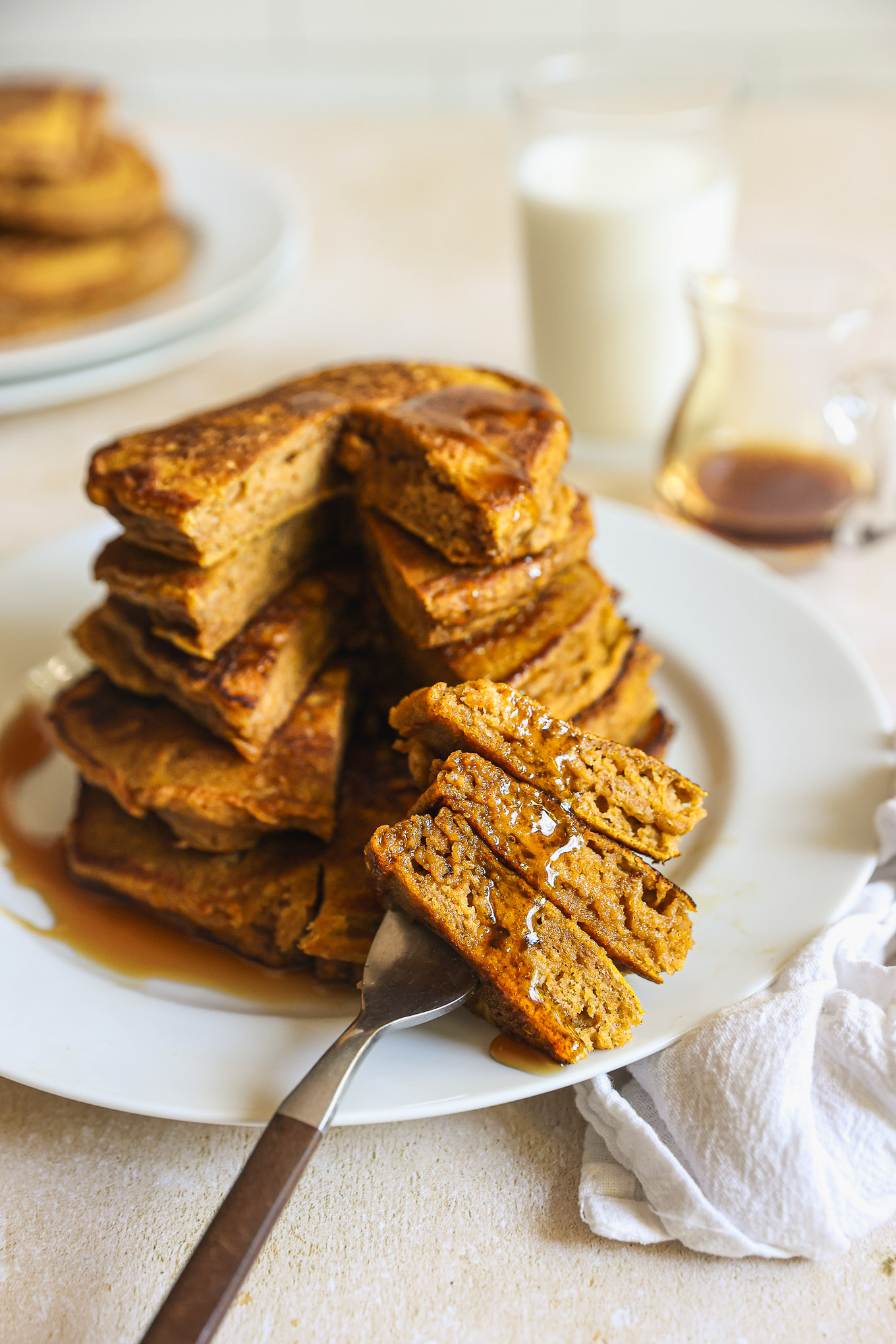 stacked and cut pumpkin spice pancakes on a plate.